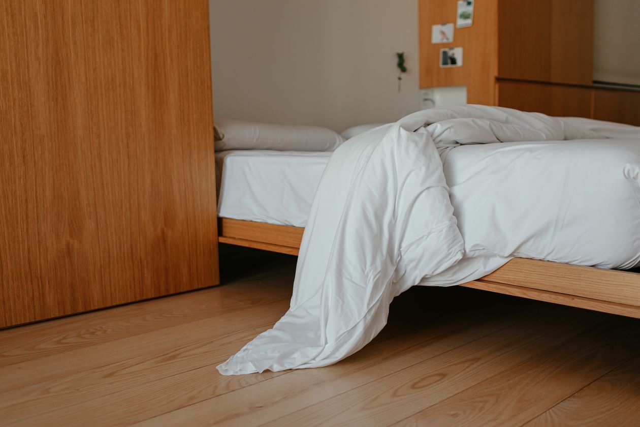 Minimalist bedroom with a wooden bed frame and white blanket, ideal for a heated blanket