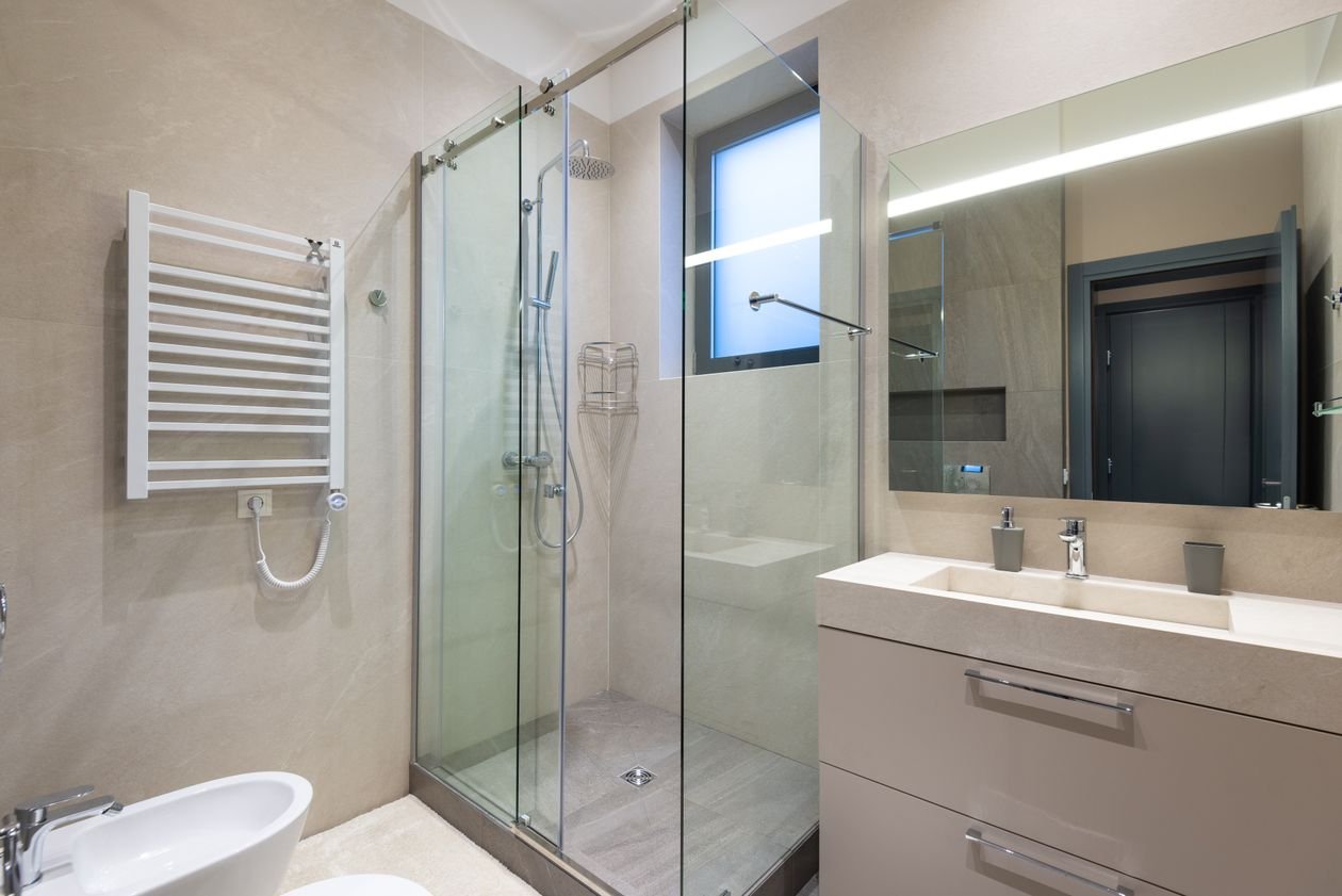Contemporary bathroom with a glass shower cabin, sink and mirror in natural tones