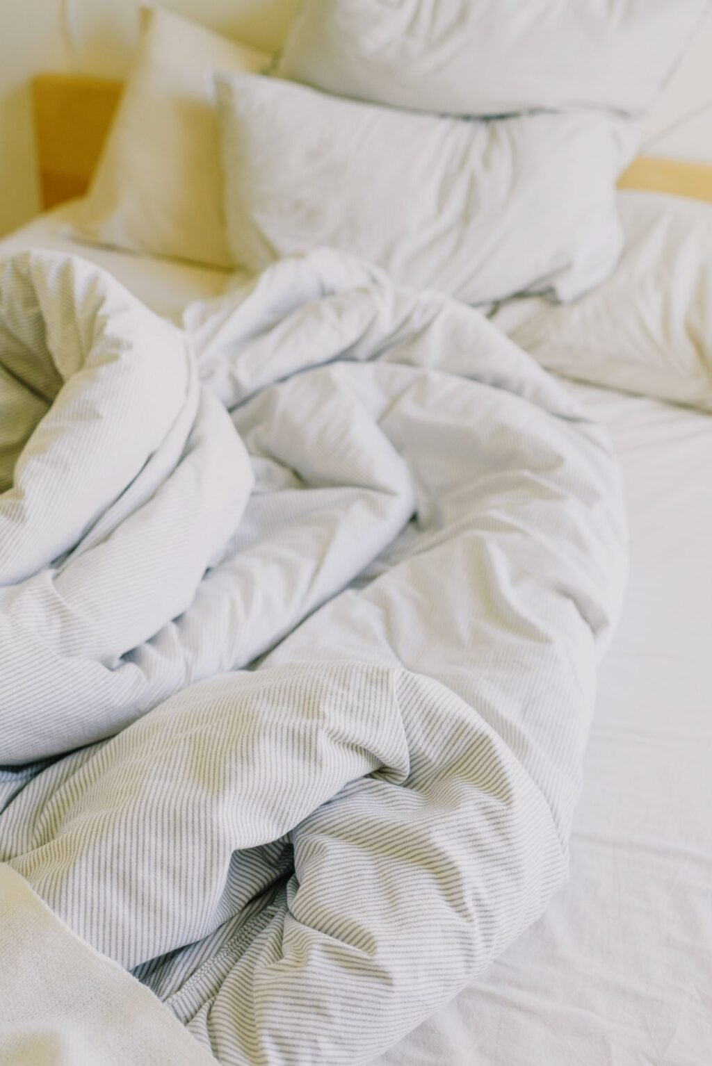 King size warming blanket and soft white bedding on a cosy unmade bed in daylight