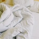 King size warming blanket and soft white bedding on a cosy unmade bed in daylight