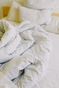 King size warming blanket and soft white bedding on a cosy unmade bed in daylight