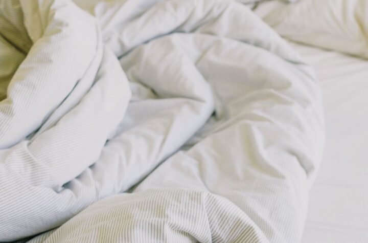 King size warming blanket and soft white bedding on a cosy unmade bed in daylight