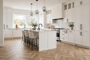 A modern kitchen with herringbone vinyl flooring in a light oak finish, laid in a zigzag pattern beside white cabinets.