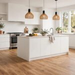 A bright modern kitchen with waterproof laminate flooring in a natural oak finish beside white cabinets.