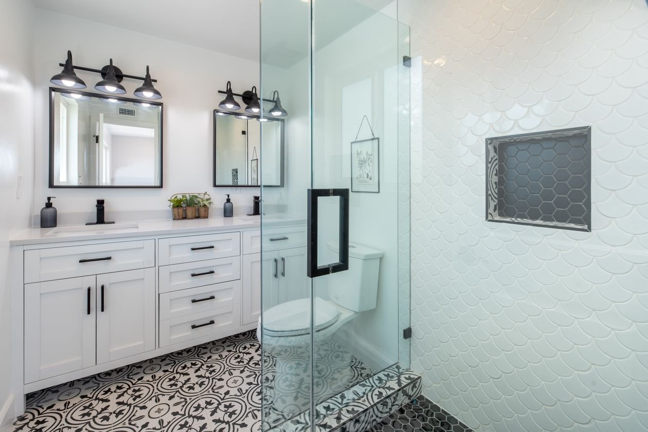 Elegant white bathroom with a glass shower and stylish patterned tile floor