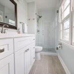 Bright modern bathroom with a glass shower, white vanity and large mirror, suited to a wet room shower tray